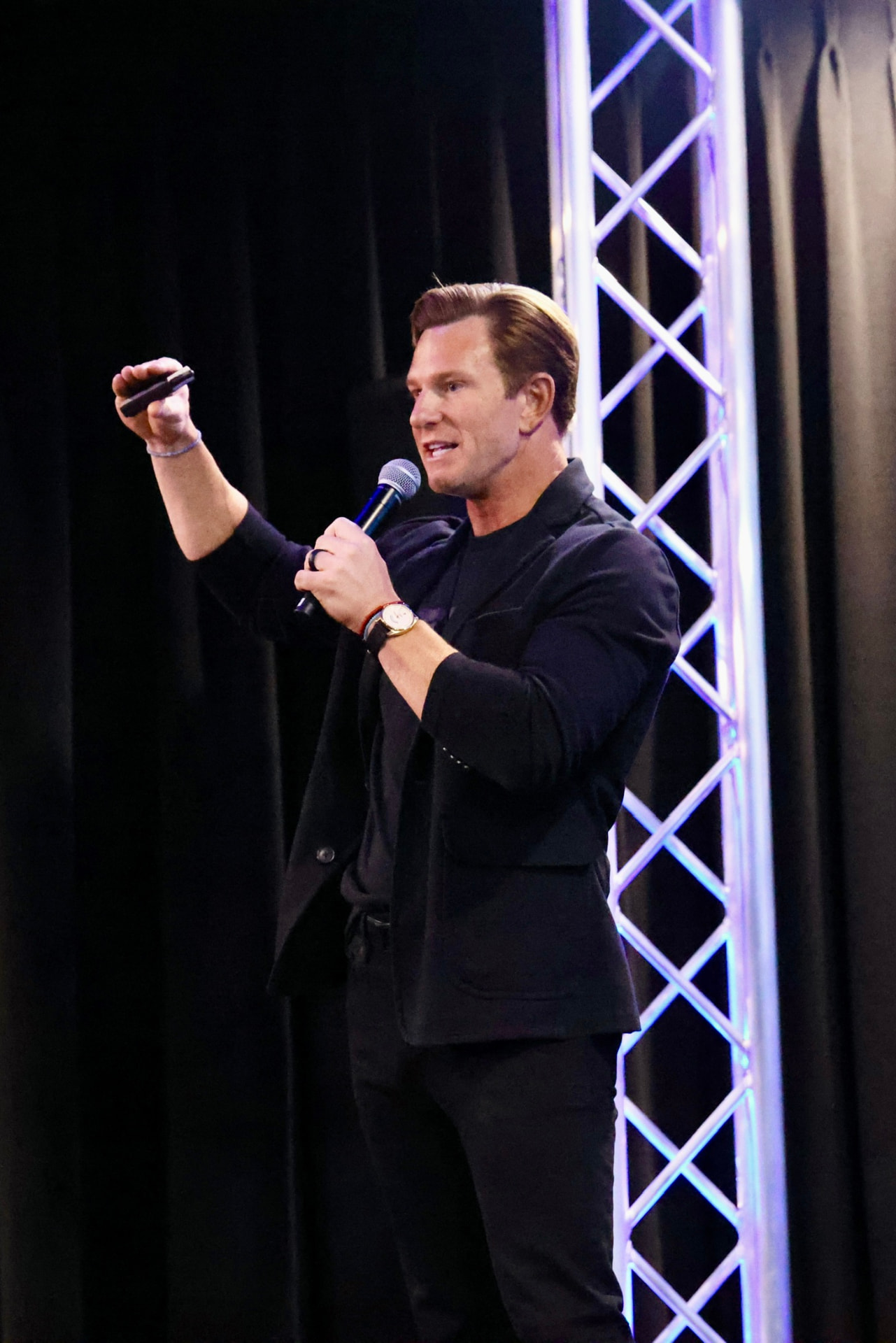 Nick Hiter speaking on stage with a microphone at a REALSUCCESS personal branding workshop